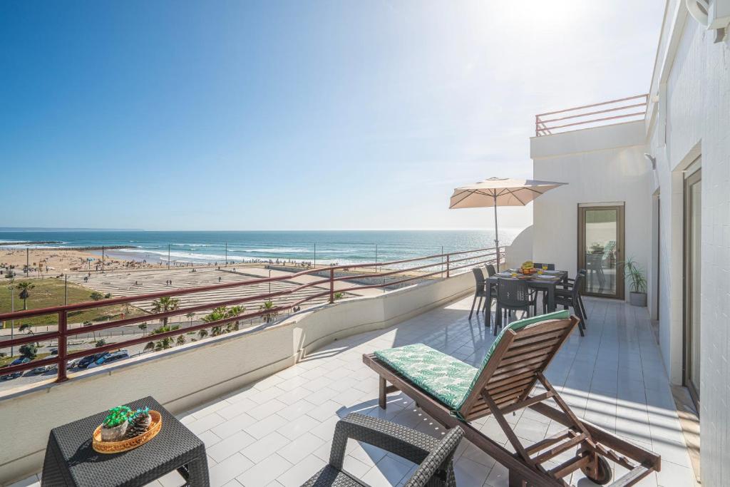 einen Balkon mit Blick auf den Strand in der Unterkunft Costa Beach Apartment by The Portuguese Butler in Costa da Caparica