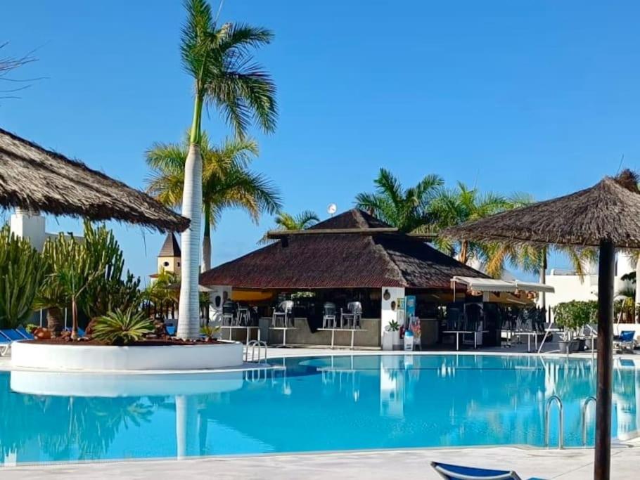 a swimming pool at a resort with palm trees at Apartamento Dhanvantari en Adeje Paradise in Playa Paraiso