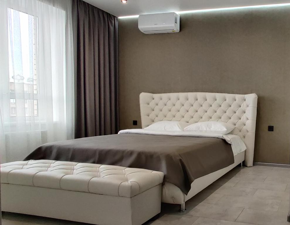 1 dormitorio con 1 cama blanca grande y cabezal de mechón blanco en Стильні апартаменти Атлант en Luts'k