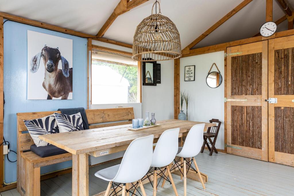 a dining room with a wooden table and white chairs at Glamping Camping NixHoeve in Genderen