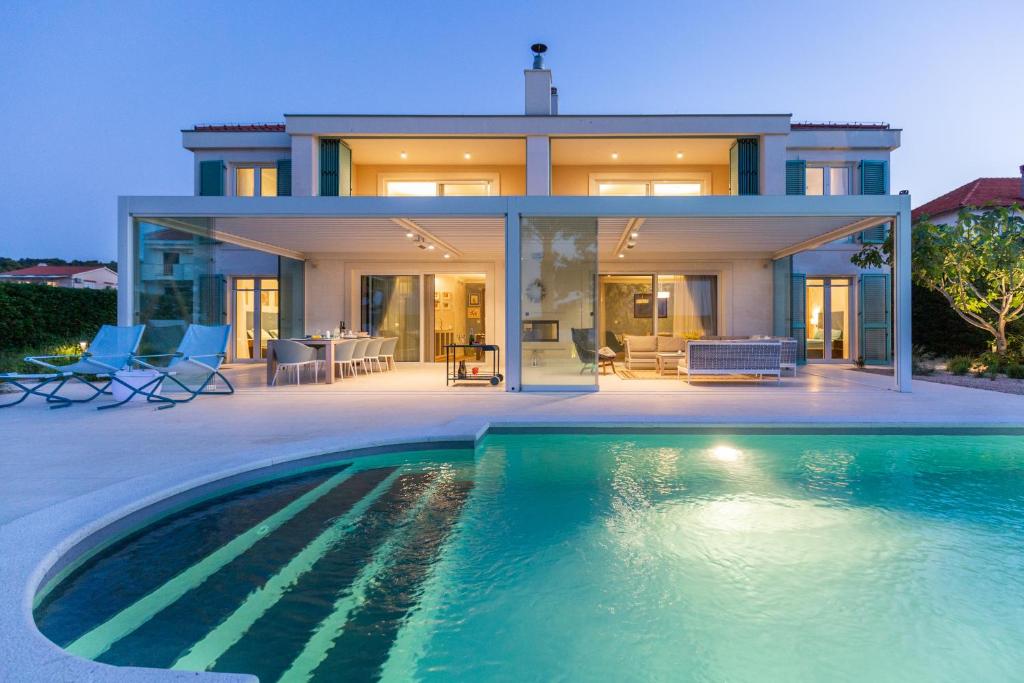 a house with a swimming pool in front of a house at DUE VILLAS Apartments - beautiful beach apartments in Dobropoljana