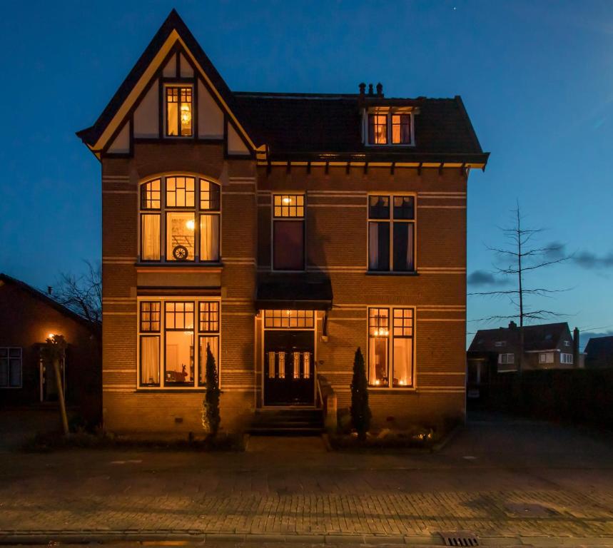 une grande maison en briques avec ses lumières allumées dans l'établissement Villa Steenwyck Giethoorn, à Steenwijk