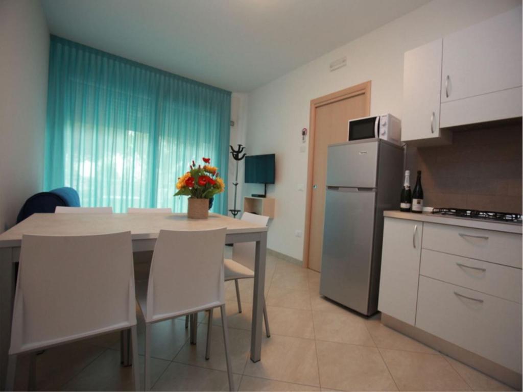 eine Küche mit einem Tisch mit Stühlen und einem Kühlschrank in der Unterkunft Elegant apartment near the beach-Beahost Rentals in Rosolina Mare