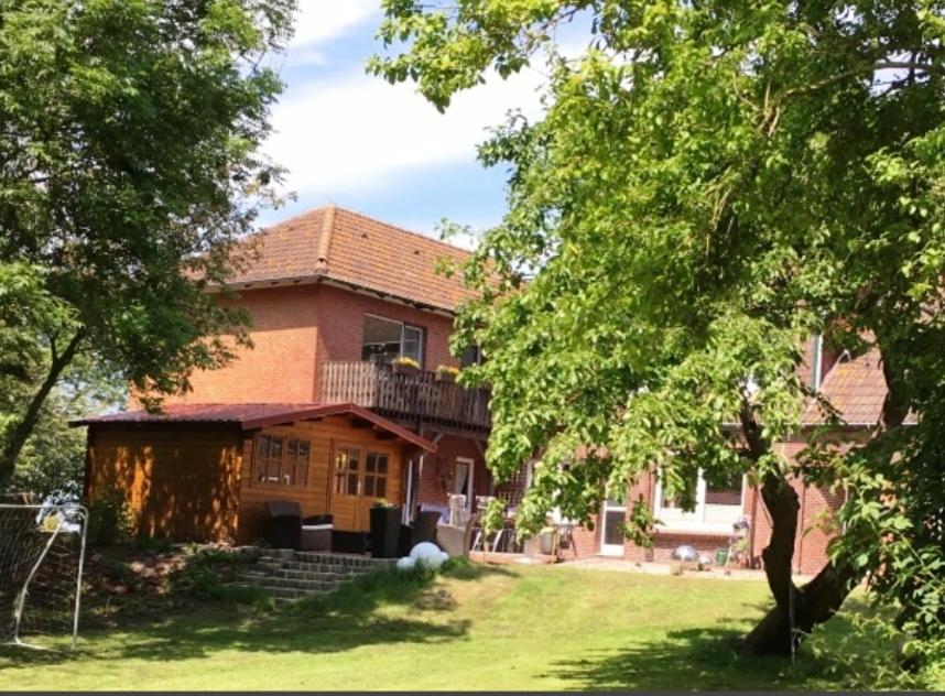 een groot bakstenen huis met een balkon in een tuin bij Buschhof Albers in Neuharlingersiel