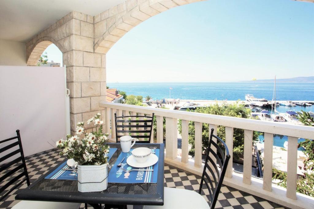 a table on a balcony with a view of the ocean at Apartments & Room Vesna in Brela