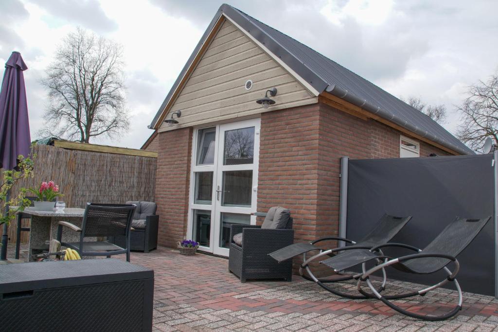a house with a patio with chairs and an umbrella at Emmen bed and breakfast in Emmen