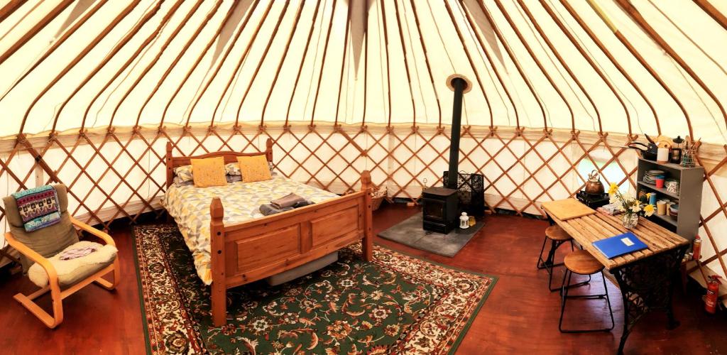 Beautiful Yurt with stunning South Downs views في Graffham: غرفة نوم في يورت مع سرير وطاولة