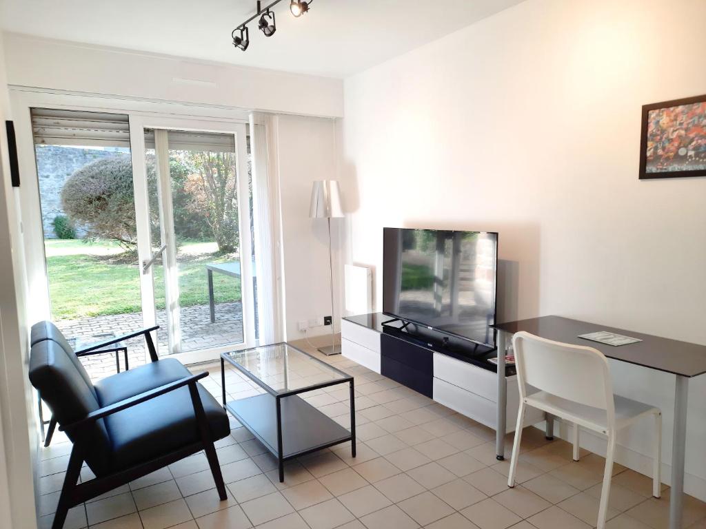 a living room with a television and a table and chairs at Ty Cocoon- Appartement avec terrasse et parking privé in Quimper