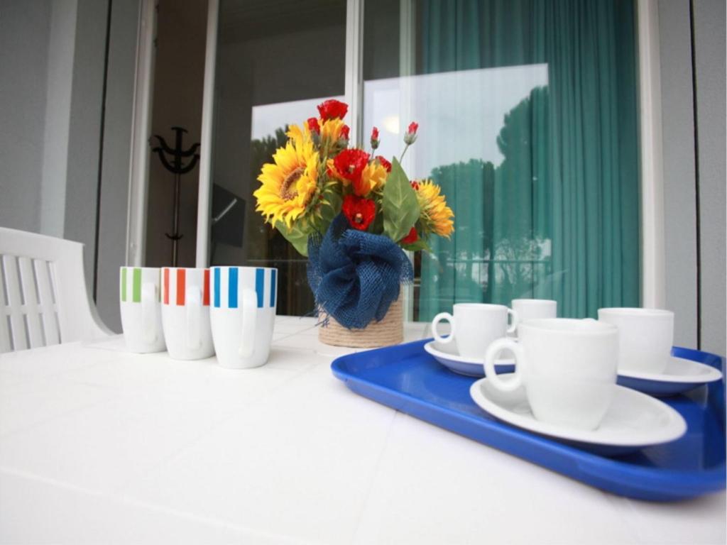une table avec des assiettes et des tasses et un vase de fleurs dans l'établissement Charming flat for up to 6 guests near the beach, à Rosolina Mare
