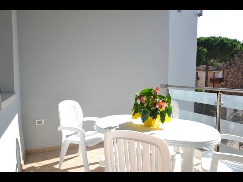 een witte tafel en stoelen met een plant op een balkon bij Modern flat in central location in Rosolina Mare in Rosolina Mare