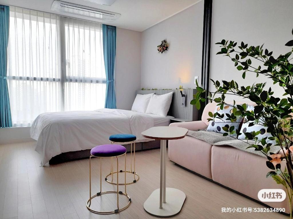 a bedroom with a bed and a couch and two stools at Well stay in Incheon