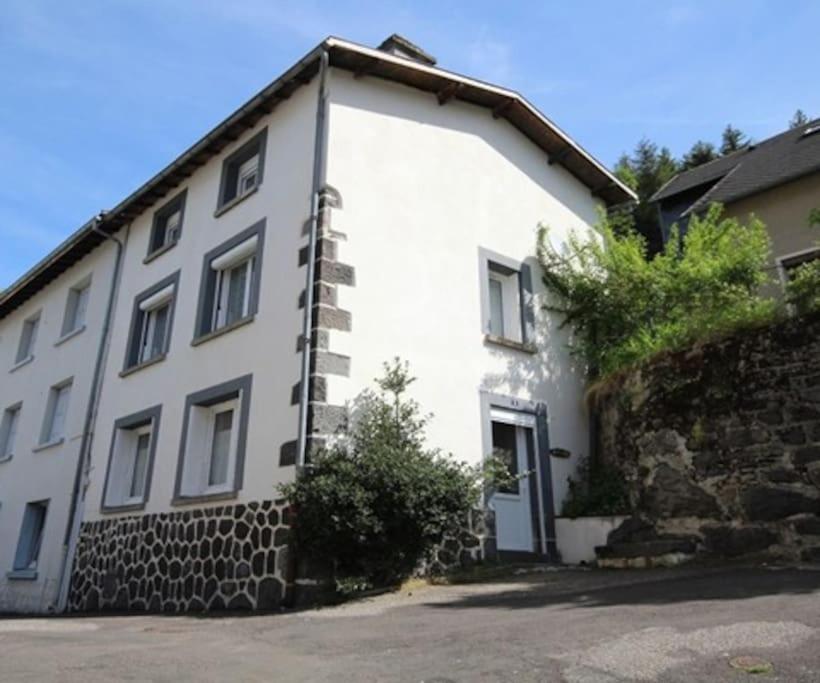 Biały dom z kamienną ścianą w obiekcie Maison 6-9 pers pour vacances et cure thermale w mieście Mont-Dore