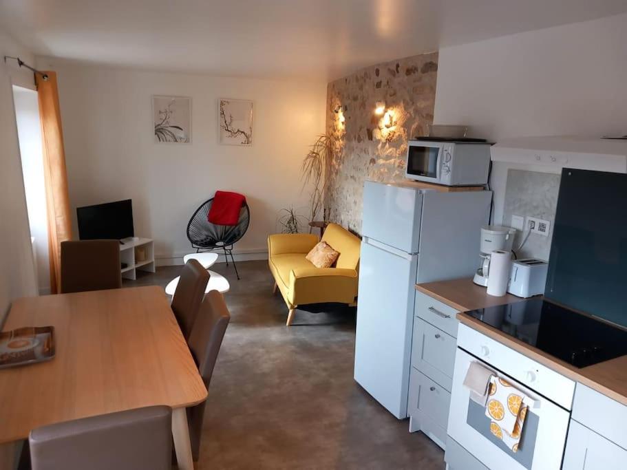 a kitchen and living room with a refrigerator and a table at Joli appartement Les Archers in Montpeyroux