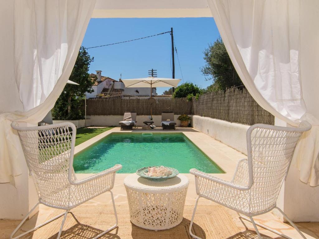 una piscina con due sedie e un tavolo di Casa Lloc Tranquil a Cala Figuera