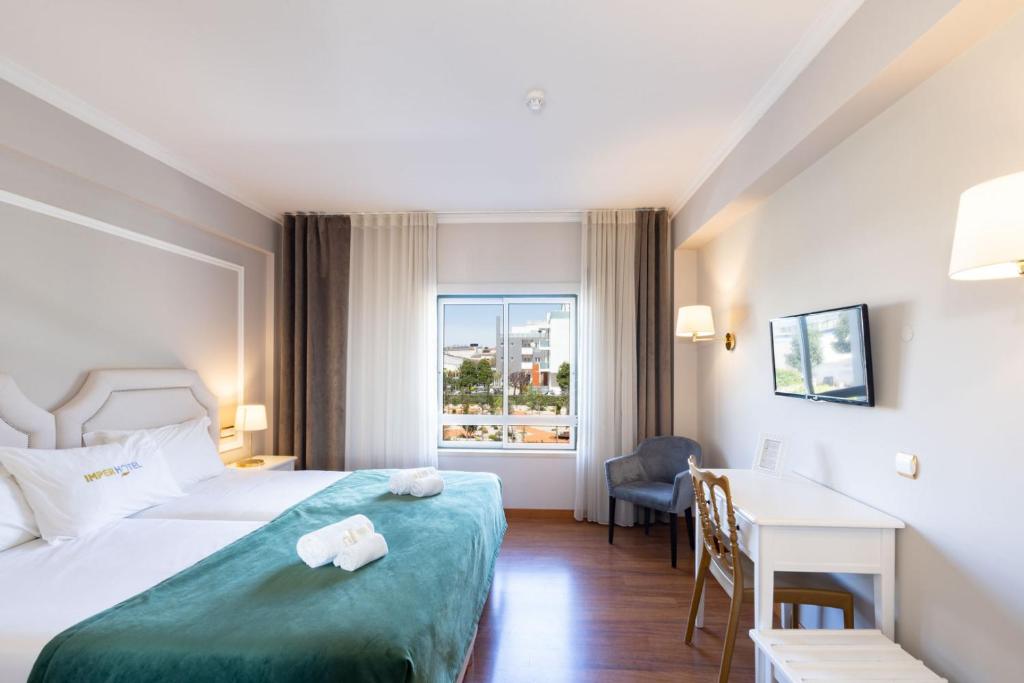 a hotel room with a bed and a desk and a window at Imperhotel by Umbral in Fátima