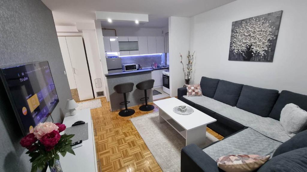 uma sala de estar com um sofá azul e uma cozinha em Aya apartment Sarajevo em Sarajevo