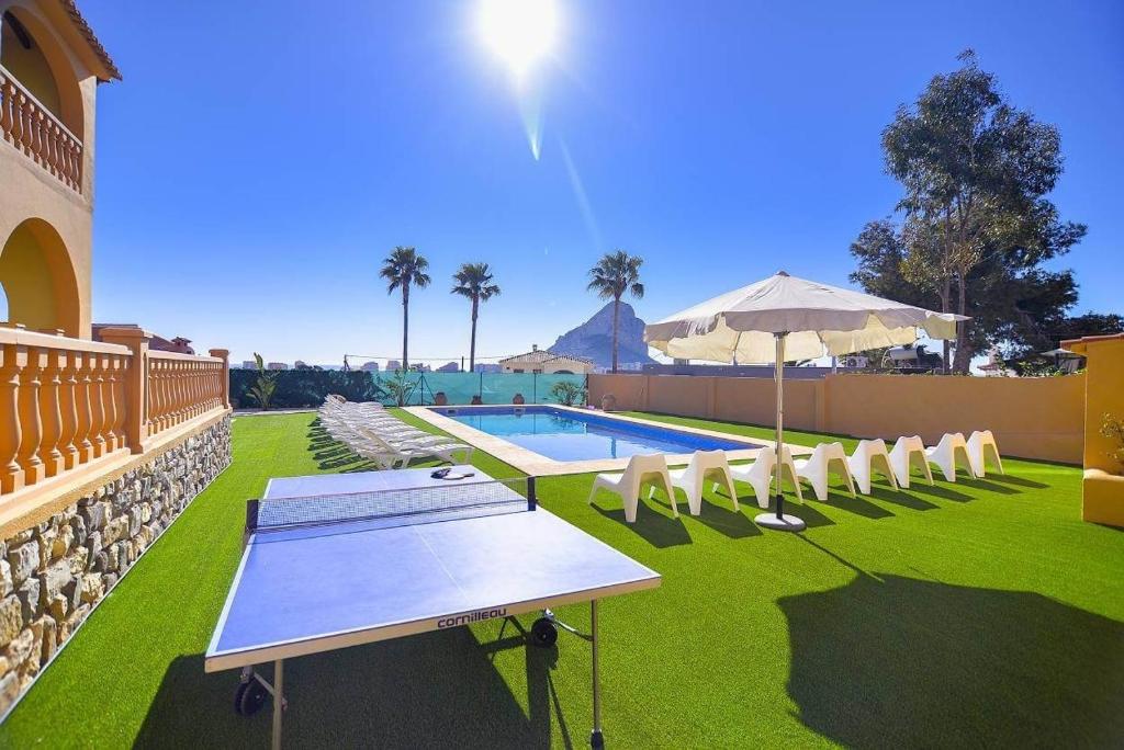a pool with chairs and a table and an umbrella at Villa Ambar - PlusHolidays in Calpe