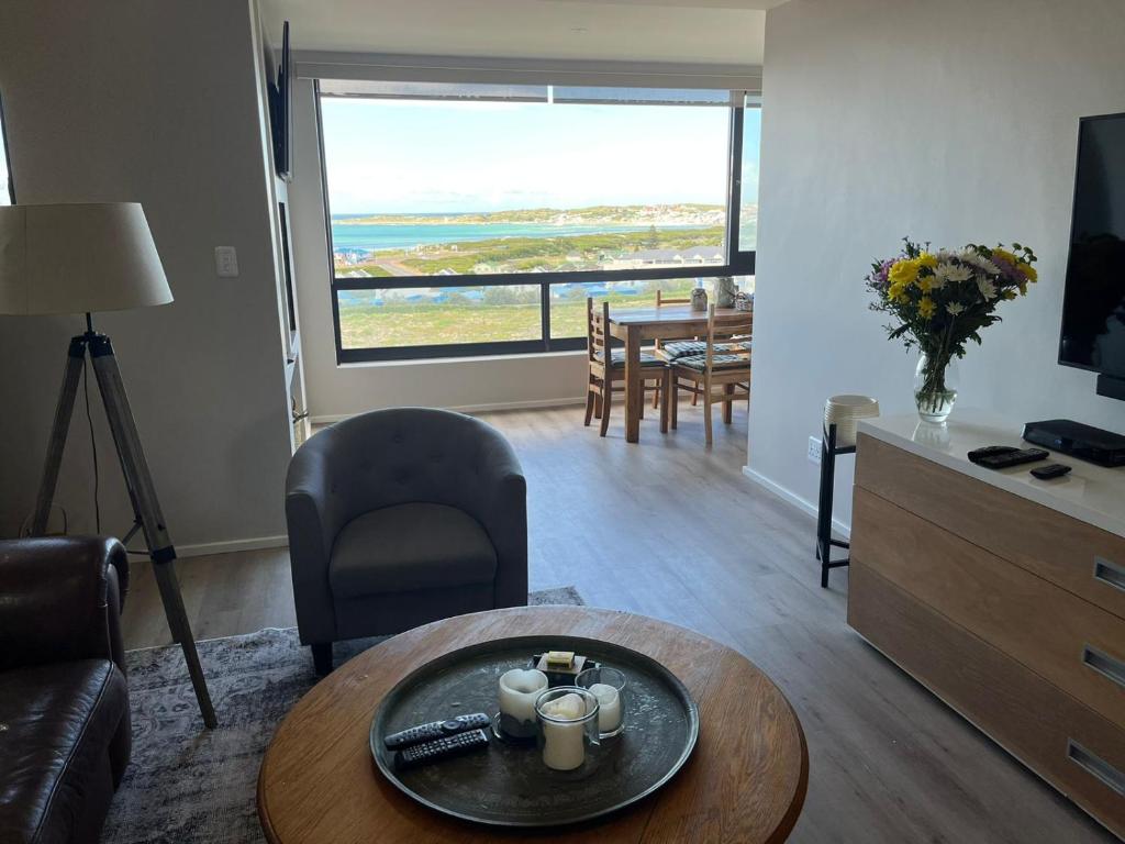 een woonkamer met een tafel en een woonkamer met uitzicht bij A Superb apartment in Still Bay in Stilbaai