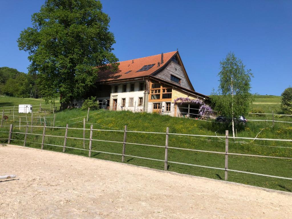 an old house on a hill next to a fence at Sérénité et nature dans une ferme équestre in Massonnens