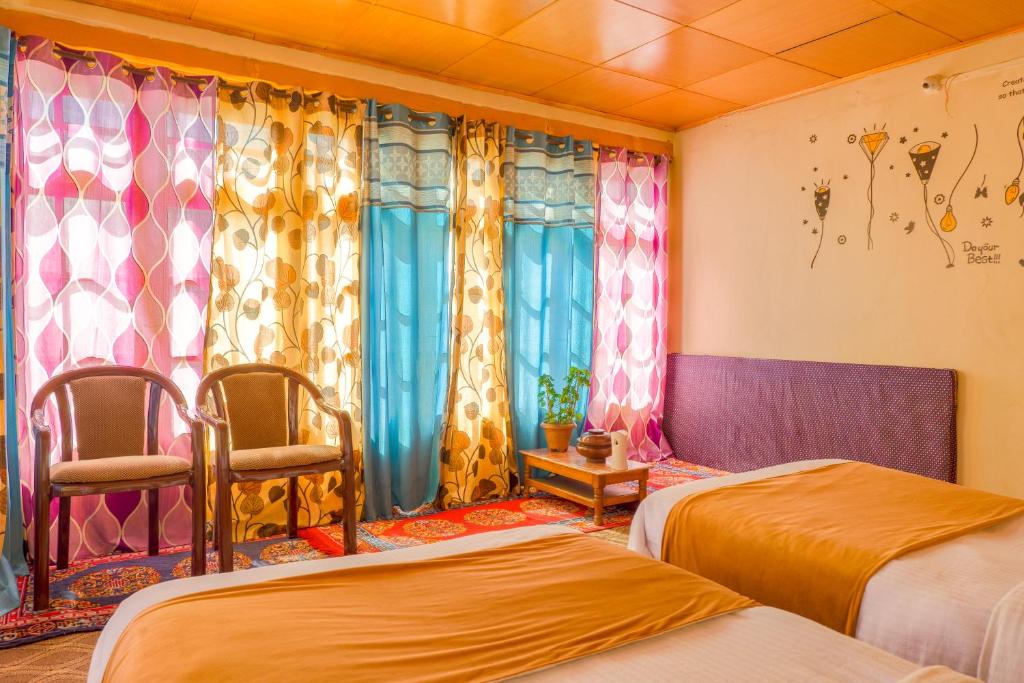 a room with two beds and two chairs and curtains at Astrostays at Pangong in Spangmik