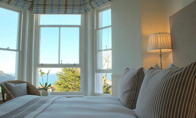 1 dormitorio con 1 cama blanca grande y ventanas en Headland House Luxury B&B, en St Ives