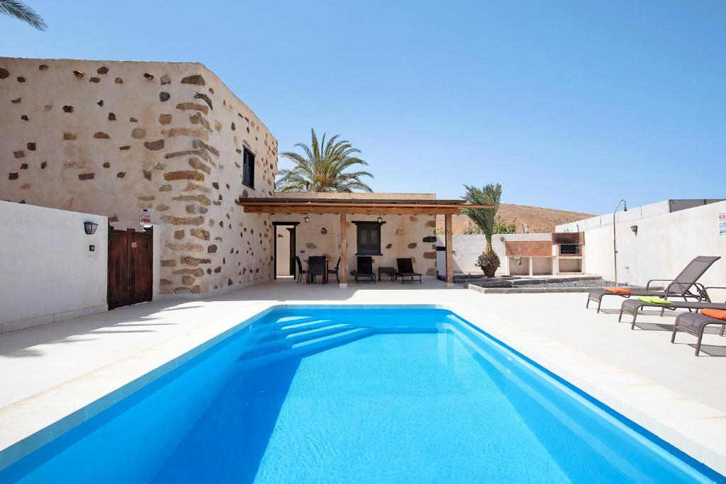 a villa with a swimming pool in front of a building at Casa Rural Andresito in Pájara