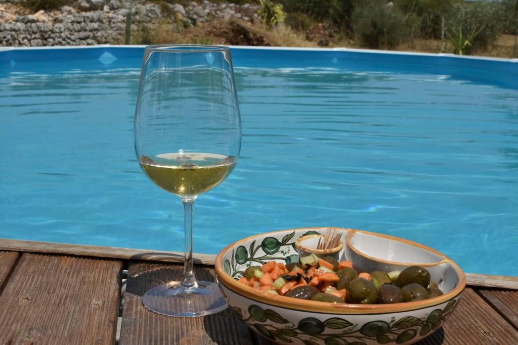 een glas witte wijn naast een kom eten bij Villa delle Stelle in Cassaro