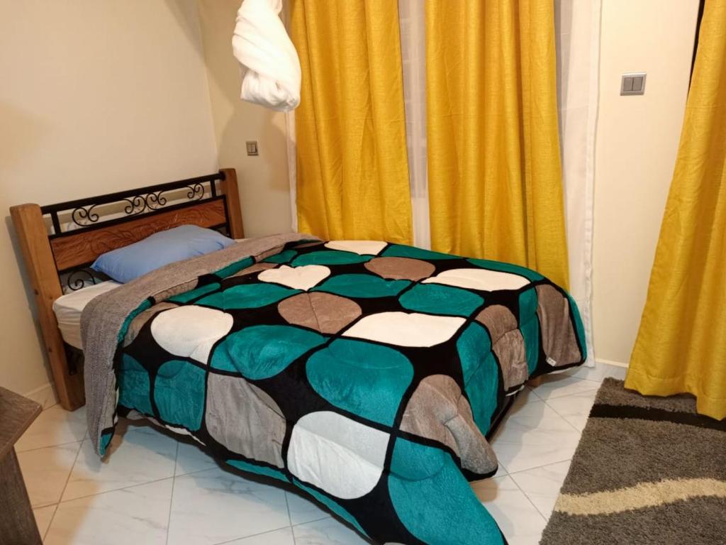 a bedroom with a bed with a colorful comforter at Comfy Haven -Rustic studio apartment in Donholm in Nairobi