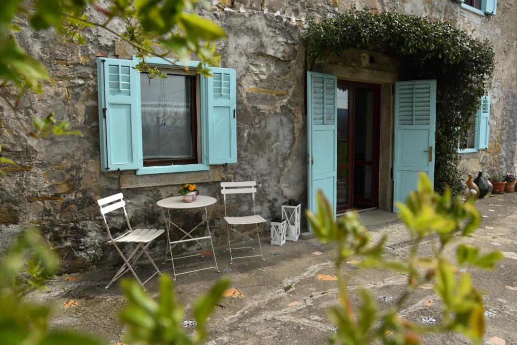 a table and chairs in front of a building with blue shutters at Villa Carla - Istrian house in Koper