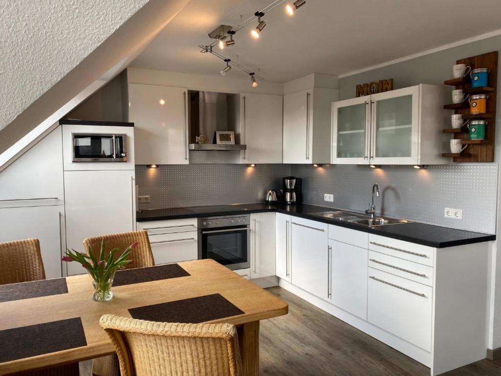 uma cozinha com armários brancos e uma mesa de madeira em Wattvogel em Greetsiel