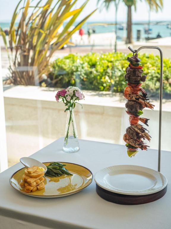 a table with two plates of food and a vase with flowers at Hotel Baia in Cascais