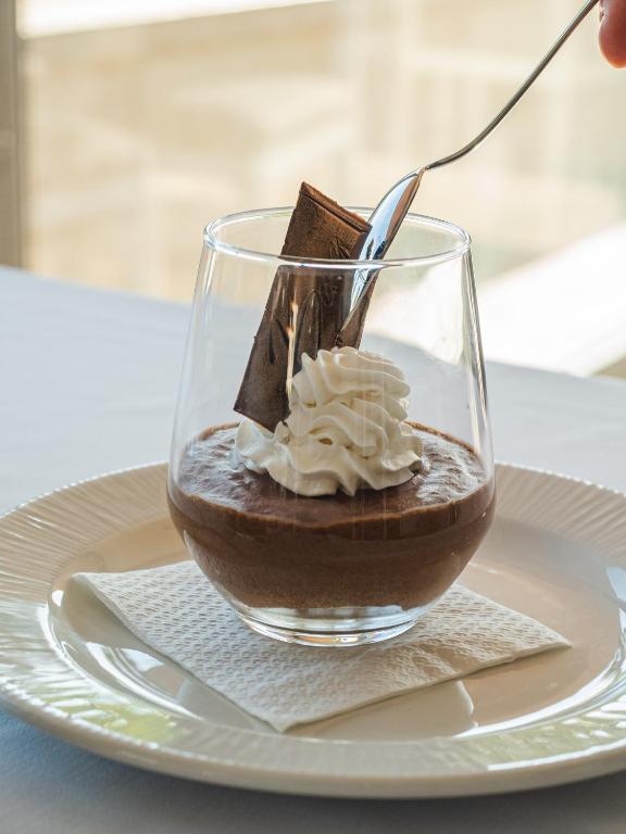 a glass of chocolate pudding on a plate with a spoon at Hotel Baia in Cascais