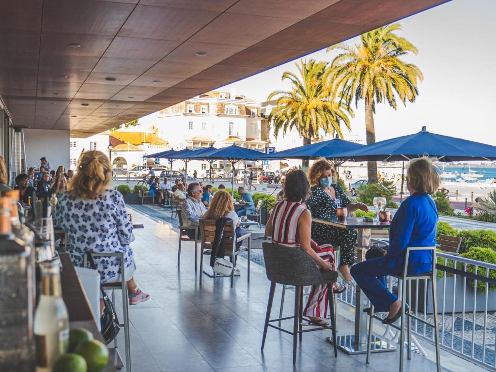 a group of people sitting at tables at a restaurant at Hotel Baia in Cascais