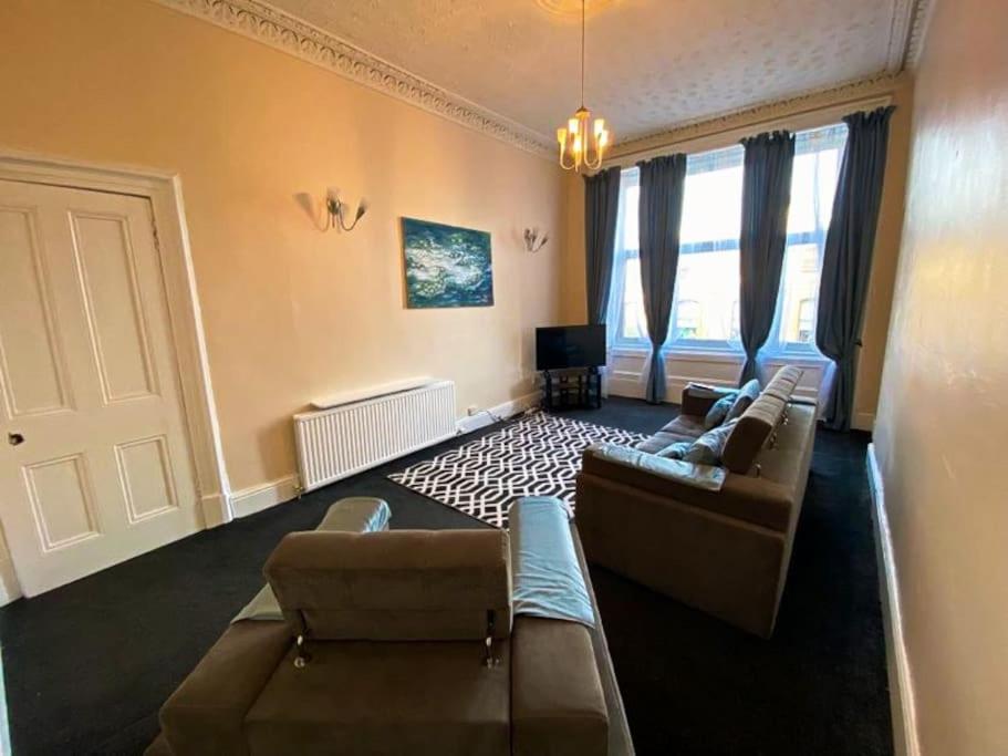 uma grande sala de estar com sofás e uma televisão em Paisley Pad: Glasgow Gateway em Paisley
