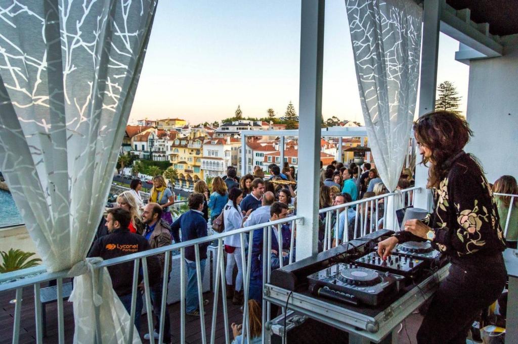 a woman standing on a balcony with a crowd of people at Hotel Baia in Cascais