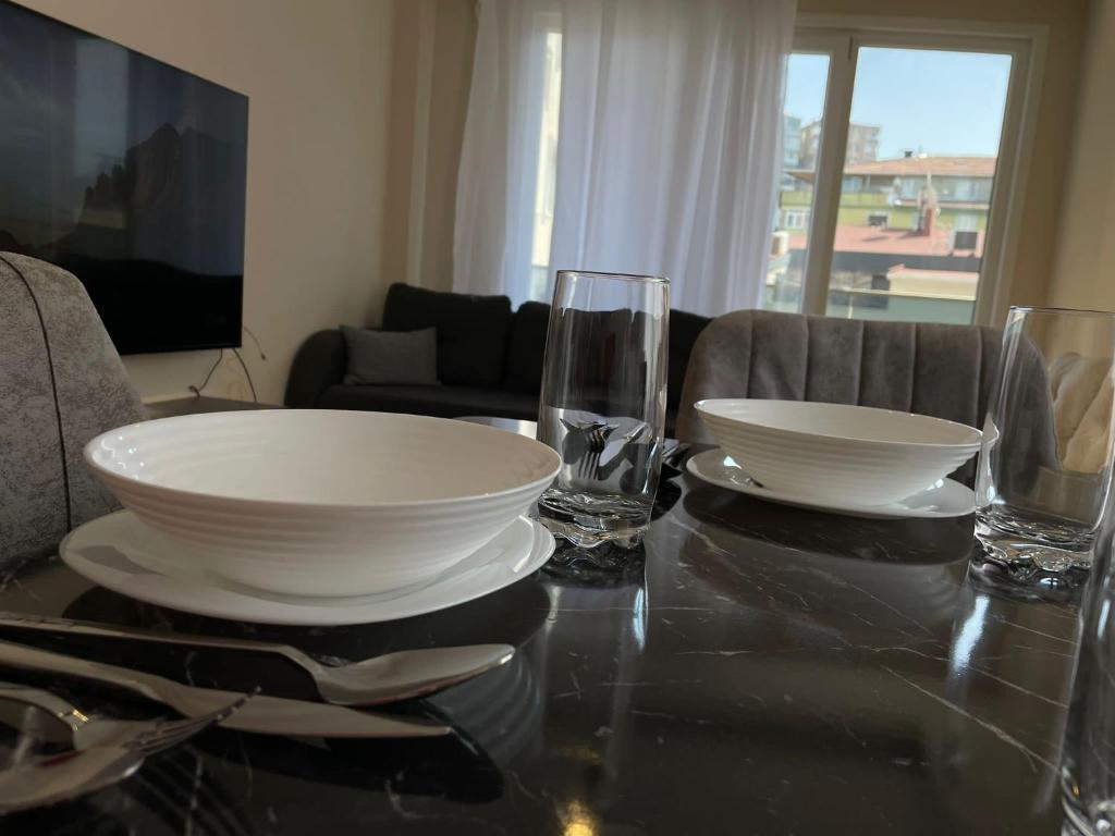 a table with two white plates and glasses on it at Trump Tower - Cevahir Shopping Center - Şişli Metro İki yatak odalı Klimalı Tüm Daire in Istanbul