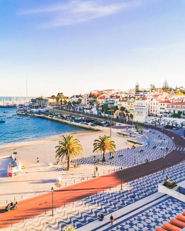 a view of a beach with blue chairs and buildings at Hotel Baia in Cascais