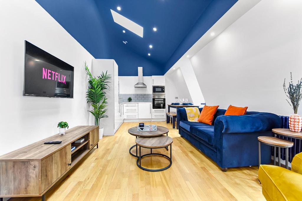 uma sala de estar com um sofá azul e uma televisão em Spacious Contemporary 2 bed flat, Central London em Londres