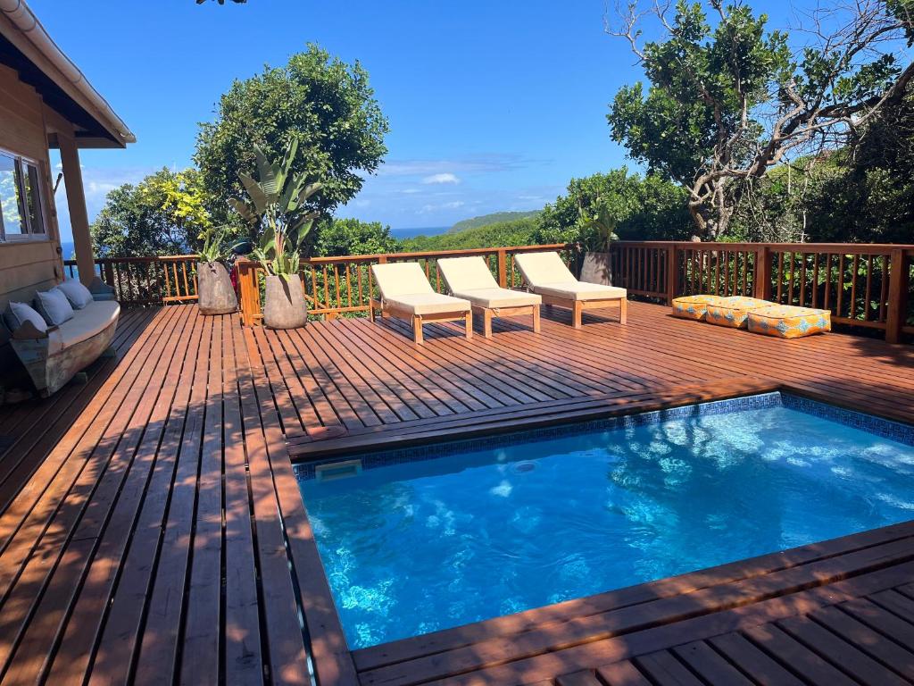une terrasse en bois avec une piscine dans une maison dans l'établissement Casa Mia, à Ponta Malangane