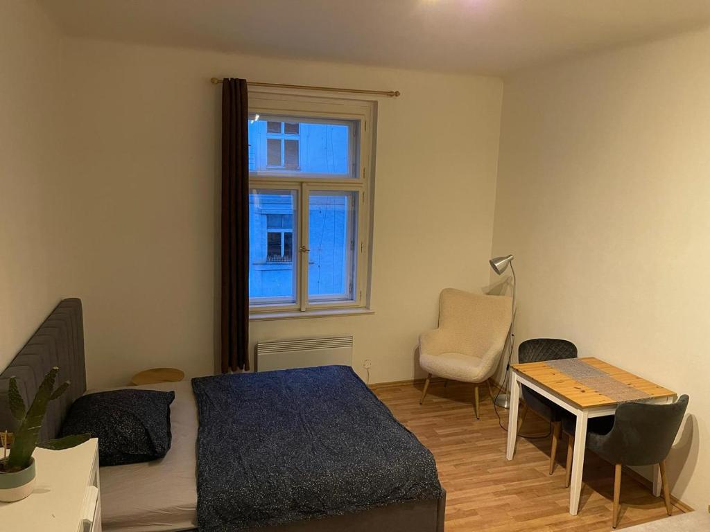 a bedroom with a bed and a table and a window at Sunlit apartment close to city center in Prague