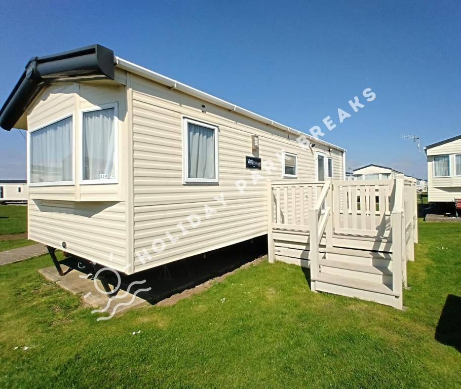 una casita blanca en un patio con una puerta en Spacious 2 bed @ Seal Bay (was Bunn Leisure), en Selsey