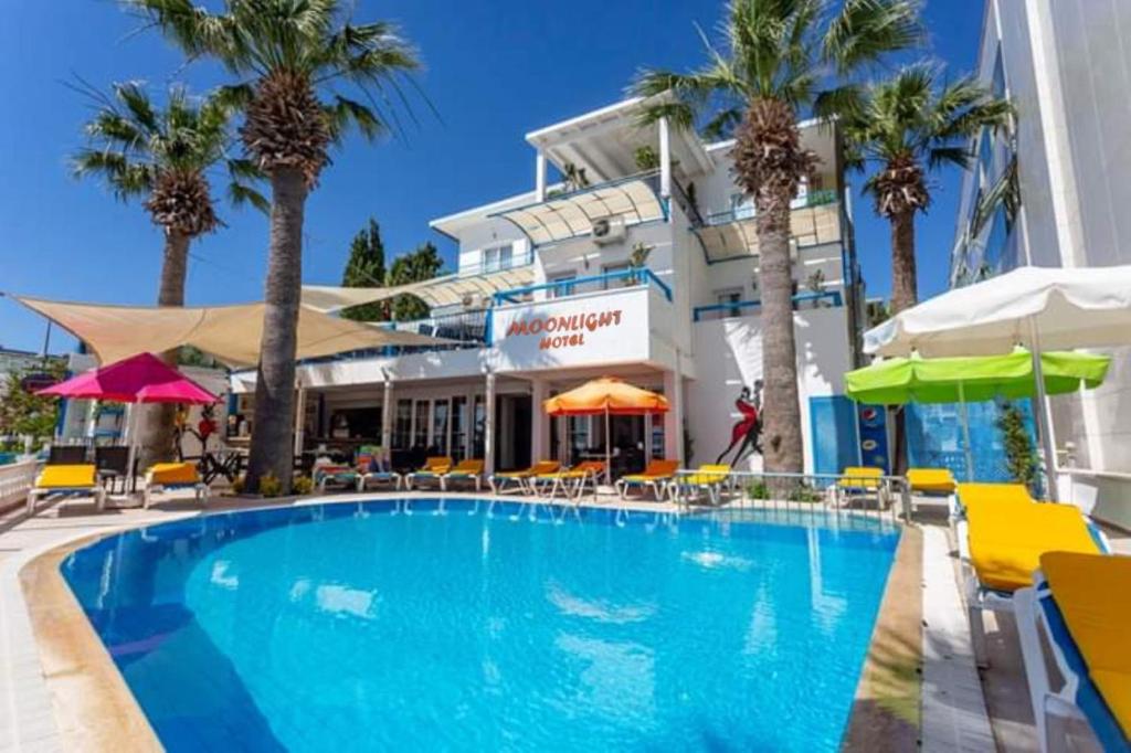 une piscine avec des palmiers en face d'un hôtel dans l'établissement Bodrum Moonlight Otel, à Turgutreis