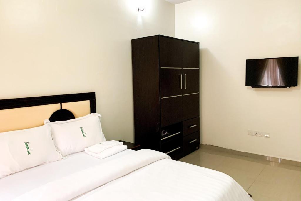 um quarto com uma cama, um armário e uma televisão em Rumens Apartment em Lagos