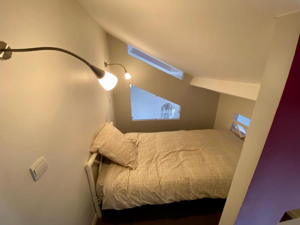 a small bedroom with a bed and a lamp at P&#39;tite maison du Parc in Orléans