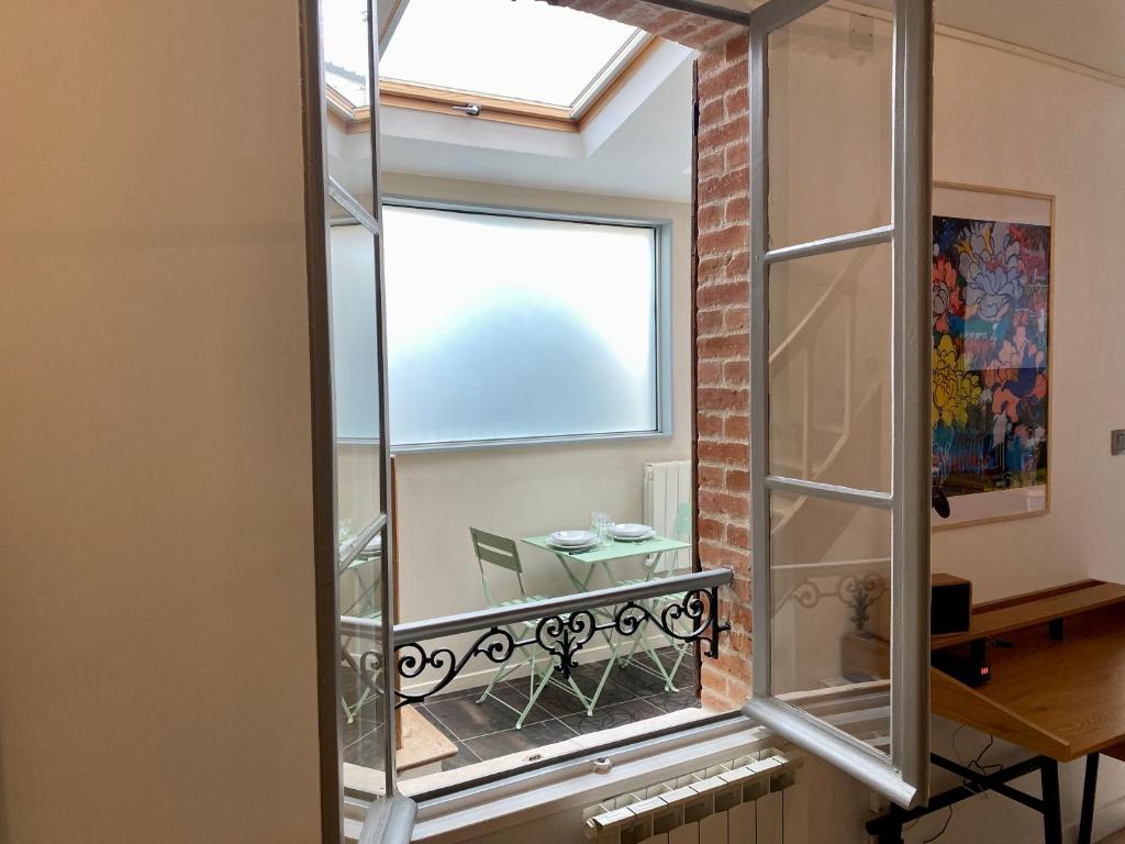 a mirror in a room with a table and a window at P&#39;tite maison du Parc in Orléans