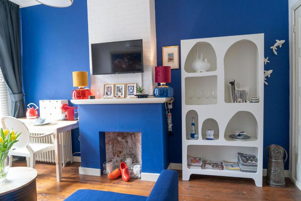 een woonkamer met blauwe muren en een open haard bij Het Kasteeltje in Vlissingen