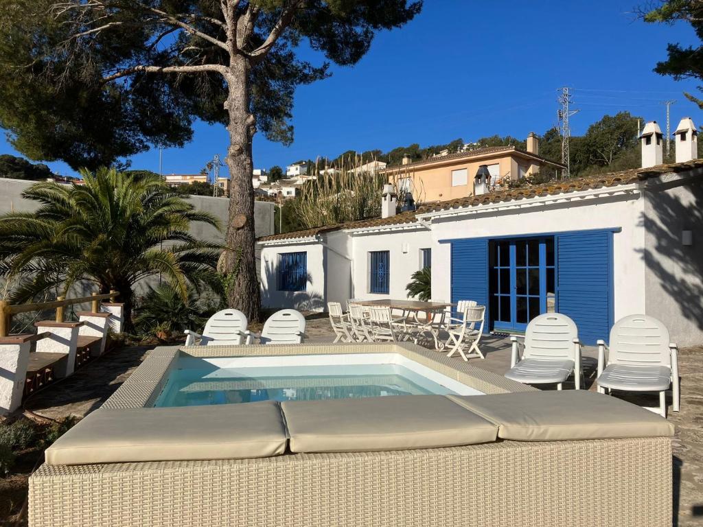 einen Pool mit Stühlen, einen Tisch und ein Haus in der Unterkunft Let's Holidays 7 Xemeneies house in Tossa de Mar