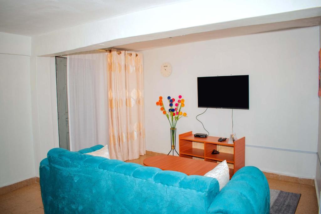 sala de estar con sofá azul y TV en Zuriel Homes 1 Bedroom apartment, en Kakamega
