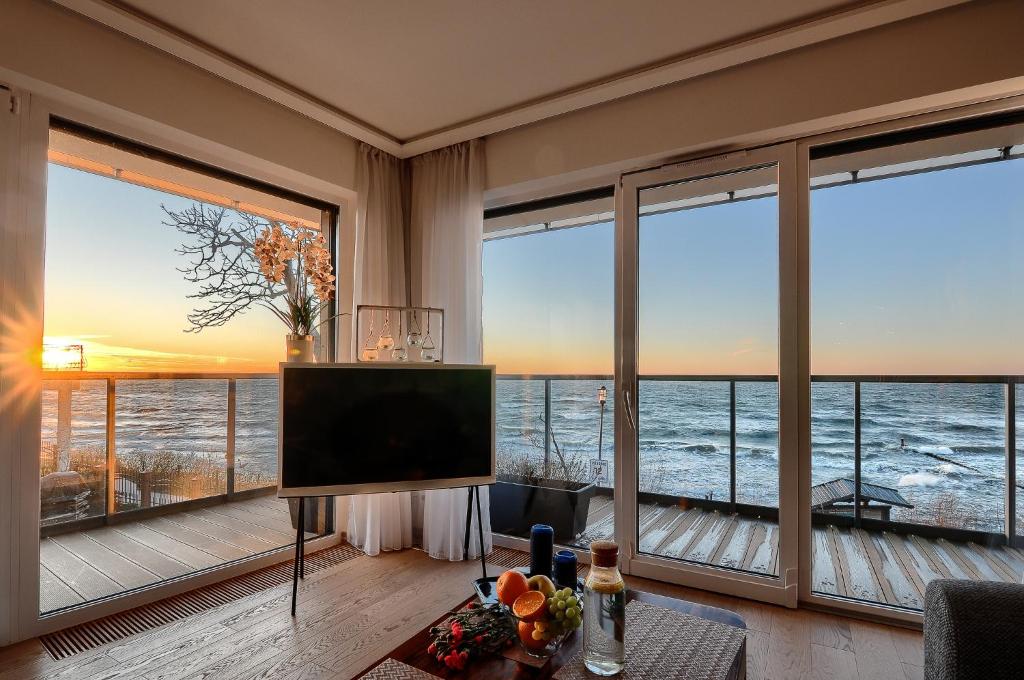 a living room with large windows and a flat screen tv at Apartament Szafirowy z BEZPOŚREDNIM WIDOKIEM na morze- Nadmorski Luksus Apartamenty in Ustronie Morskie