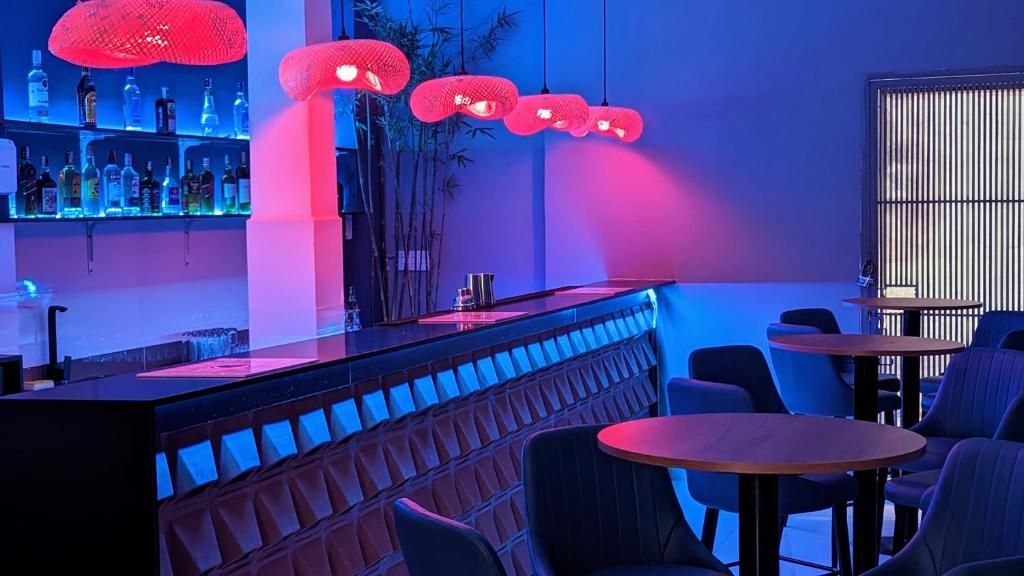 um bar com duas mesas e cadeiras e iluminação roxa em Base Backpackers em Cidade de Ho Chi Minh